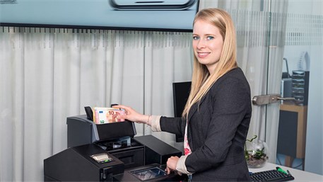 Mitarbeiter*in bedient Geldzaehlmaschine